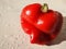 Object isolate Bulgarian sweet red pepper in drops of water on the surface of the white kitchen table in natural light from the wi