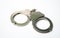 Object is a unilateral handcuff made of iron, single lock, on a white background, symbolizing the law and the offense.