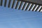 Oblique view looking up through slats of a pergola at blue sky and power lines