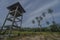 Observation tower with palm trees over blue sky with clouds