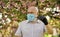 observe precautions while pandemic. healthy life. wear mask in blossoming pink sakura park. man at sakura in protective