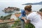 Observing place with coin operated telescope is on the hill of the Sveti Stefan town. Woman looking at the same name island. Monte