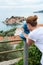 Observing place with coin operated telescope in the Sveti Stefan town. Woman looking at the same name island. Adriatic sea, Monten