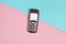 Obsolete button phone with a screen for copy space on a pastel background. Minimalist trend