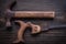 Obsolete rough handsaw and claw hammer on vintage wooden board