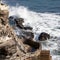 The Ocean against the rocks of the cliff at day time, wave splash and sea foam