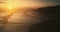 Ocean bay waves at sunset slow motion aerial view. Cliff coast silhouette on sun light sky backdrop.