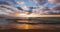 Ocean beach and golden sunrise. Sea sand and washing waves on the coast.