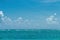 Ocean coastline, emerald water, a small sailboat near the horizon