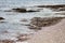 Ocean in Cornwall in the daytime, waves lapping on to the stony shore