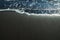 Ocean foam covering wonderful black sand beach of Tenerife island