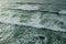 Ocean foamy waves approaching rocky shore. Top view