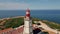 Ocean lighthouse standing sunny coast over endless marine horizon aerial view.