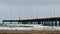 Ocean pier with waves, surfers and sand on an overcast cloudy day