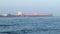 Ocean sailing oil tanker ship approaches the waters of the Gulf of Mexico in Port Aransas, Texas on a hazy evening, with waves and