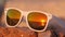 Ocean sunset reflected in sunglasses lying on the stone