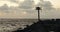 Ocean at sunset viewed from jetty with harbor light and horn