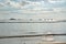 Ocean transport shipping vessels anchored far from the shore under cloudy skies