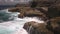 Ocean water breaks on rocks on bright sunny day