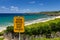 Ocean Waters Cause Many Hazards sign with view of Oneloa Beach, Maui, Hawaii