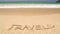 Ocean wave approaching word travel written in sand on beach