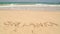 Ocean wave approaching words Sri Lanka written in sand on beach