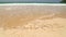 Ocean wave covering word holidays written in sand on beach