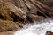 Ocean Waves Crash on Base of Cliffs as Man Climbs on Rocks