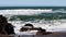 Ocean Waves Hitting Rocks On Sandy Beach Surfer In Background