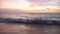 Ocean waves roll on empty sandy beach under beautiful sky