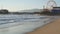 Ocean waves and sandy california beach, classic ferris wheel in amusement park on pier in Santa Monica pacific ocean resort.
