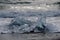 Ocean waves splash around blue ice on the shore of an Iceland Beach