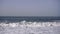 Ocean weaves and surfers on black sand beach