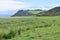 Oceanside landscape with a green rolling hill ranch along the road to Hana on the island of Maui