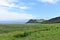 Oceanside landscape with a green rolling hill ranch along the road to Hana on the island of Maui