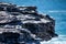 Oceanside rocky cliff top with blue coastal sea in background