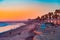 A Oceanside sunset at the beach draws people to it to walk and relax