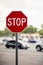 Octagonal red and white stop sign in the foreground of a busy parking lot