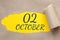 october 02. 02th day of the month, calendar date.Hole in paper with edges torn off. Yellow background is visible through