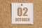 october 02. 02th day of the month, calendar date.White calendar sheet attached to brown cork board.Autumn month, day of