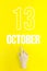 October 13rd. Day 13 of month, Calendar date.Hand finger pointing at a calendar date on yellow background.Autumn month, day of the