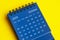 October 2025 blue desk calendar on yellow cover background.