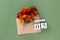 October 5. Bouquet of orange flower in craft envelope and calendar date on green background. Minimal concept Hello fall. Template