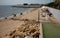 Odessa, Ukraine -2022: Metal military barriers, anti-tank hedgehogs on sea city beach. Vacationers sunbathe next to iron anti-tank