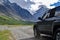 Off-road SUV car with Aktru mountain valley and glacier background. Adventure travel concept. Adventure tourism.