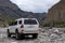 Off road suv moving on rocky bottom of dried river. Outdoor landscape. Adventure travel. Off road trail concept. Offroad car.