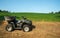 Off road vehicle atv alongside lush green soybean field