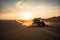 off-road vehicle speeding over dunes in the desert, with a dramatic sunset in the background