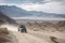 off-road vehicle speeding through vast and rugged landscape, with mountains in the background