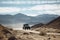 off-road vehicle speeding through vast and rugged landscape, with mountains in the background